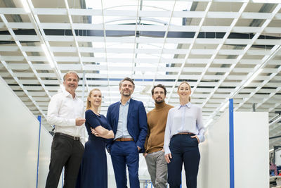 Happy businessman with colleagues standing together at industry