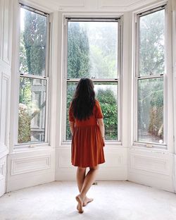 Rear view of woman standing against window