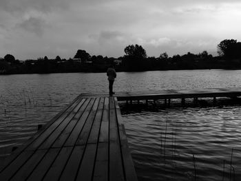 Rear view of man on pier over lake