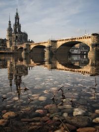 Arch bridge over river against buildings