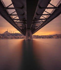 Low angle view of bridge over river against sky during sunset