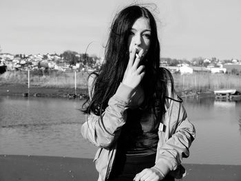 Woman smoking while standing against lake