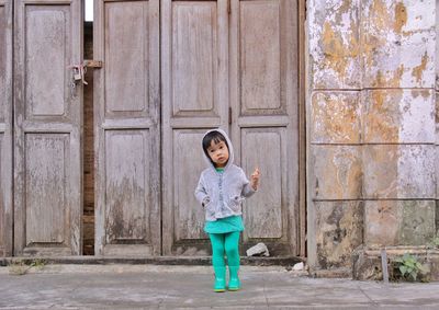 Full length of cute girl standing against wooden doors