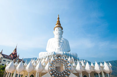 Low angle view of white buddha statues at wat pha son kaew against sky