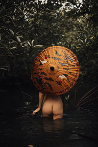 Low section of naked woman holding chinese antique umbrella 