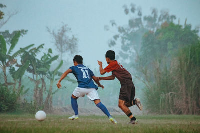 Rear view of man playing soccer on field