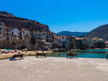 People at waterfront against blue sky