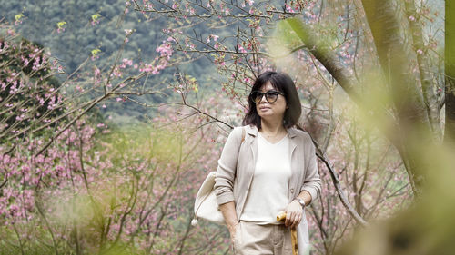 Woman standing by tree against plants