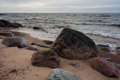 Rocks on beach against sky during sunset