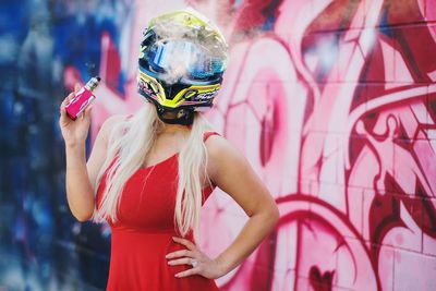 Midsection of woman standing against pink wall