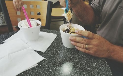 Midsection of man having ice cream on table