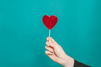 Midsection of woman holding heart shape over white background