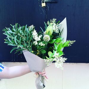 Cropped image of hand holding bouquet against door