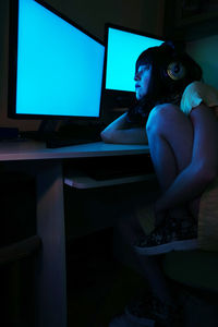 Side view of woman using computers in darkroom