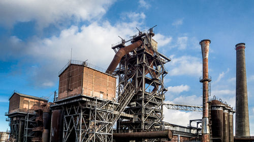 Low angle view of crane against cloudy sky