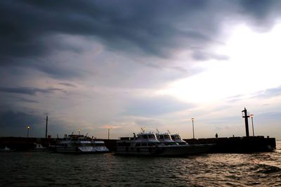 Sailboats moored on sea against sky during sunset