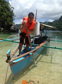 Man rowing boat in sea against sky