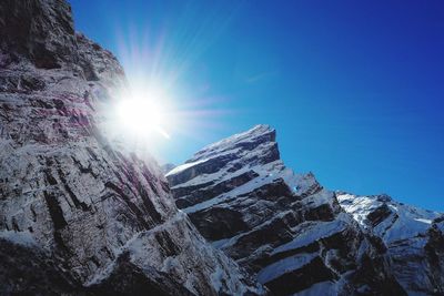 Low angle view of snowcapped mountains against blue sky