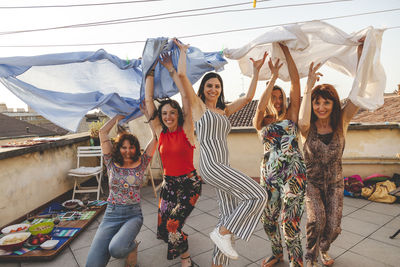 Portrait of cheerful friends jumping on building terrace