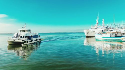 Boats moored on sea against clear blue sky