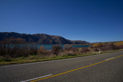 Road by mountains against clear blue sky