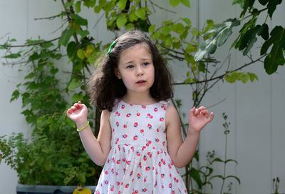 Expressive young girl in the summer dress enjoying the backyard