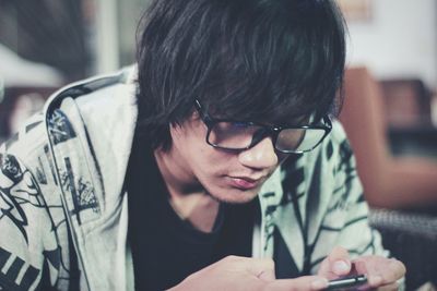 Close-up of young man using smart phone sitting at home