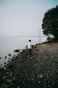 Side view of man standing by sea against sky