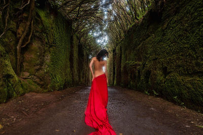 Shirtless woman wrapped in red fabric at forest