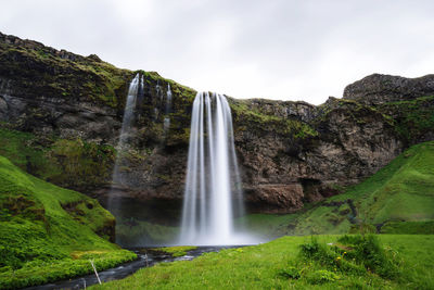 Scenic view of waterfall against sky