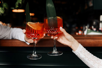 Hands of woman and man are clinking, cheers with glasses of spritz cocktail. couple celebrating 