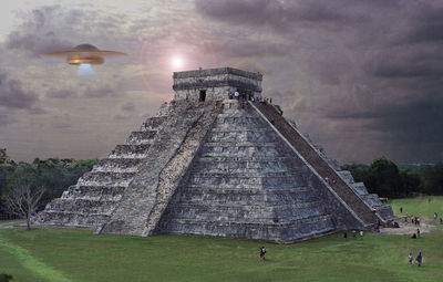 People at historical building against cloudy sky