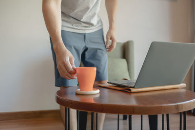 Midsection of woman standing on table at home