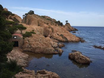 Rocks by sea against sky