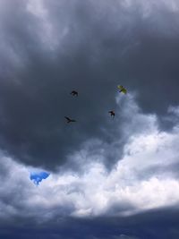 Low angle view of birds flying in cloudy sky