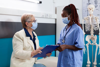 Rear view of female doctor examining patient in hospital