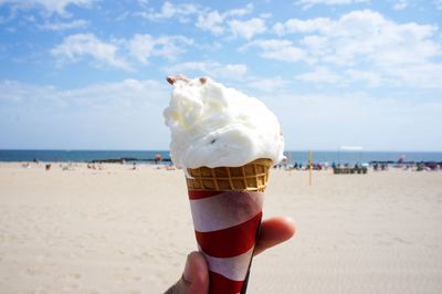 Close-up of hand holding ice cream cone at beach