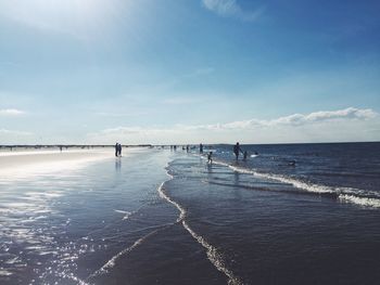 People at brancaster beach against blue sky