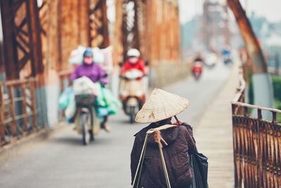 Rear view of man wearing hat walking on bridge