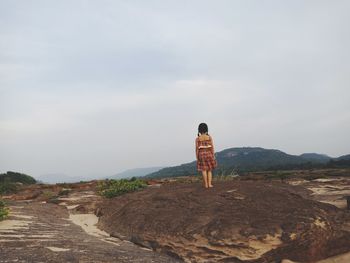 Rear view of woman standing on mountain against sky