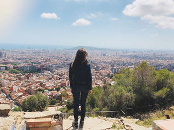 Rear view of woman standing by buildings against sky