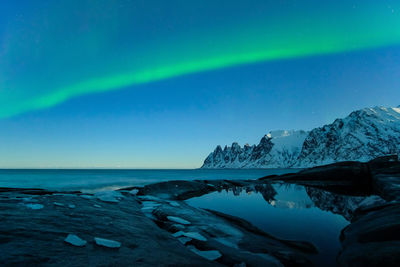 Aurora borealis over sea against sky at night