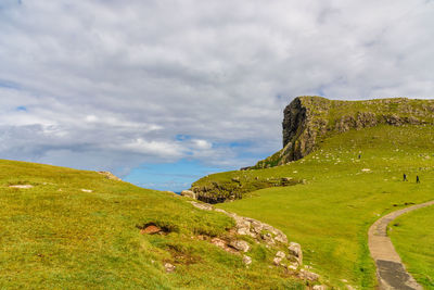 Scenic view of green landscape against cloudy sky