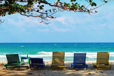 Chairs on beach against sky