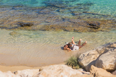 High angle view of man relaxing on rocks at beach