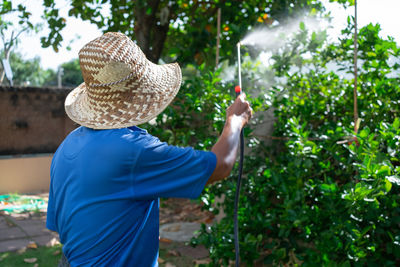 Rear view of man spraying pesticide on plant