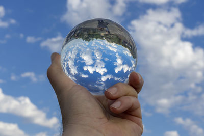 Low angle view of hand holding glass against sky