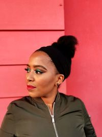 Portrait of woman standing against red wall