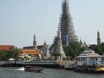 Wat arun by chao phraya river against sky in city