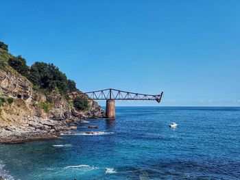 Bridge over sea against clear blue sky